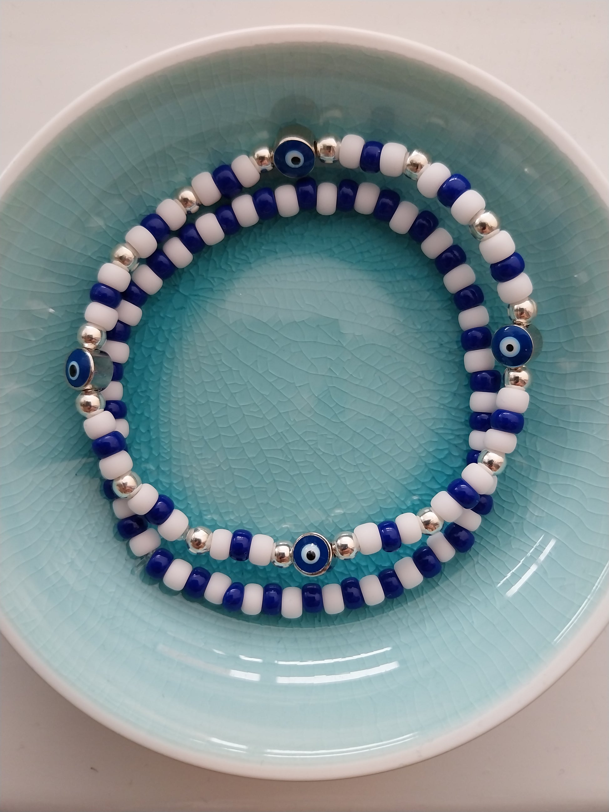 A pair of blue and white bead bracelets one of them features evil eye charm beads