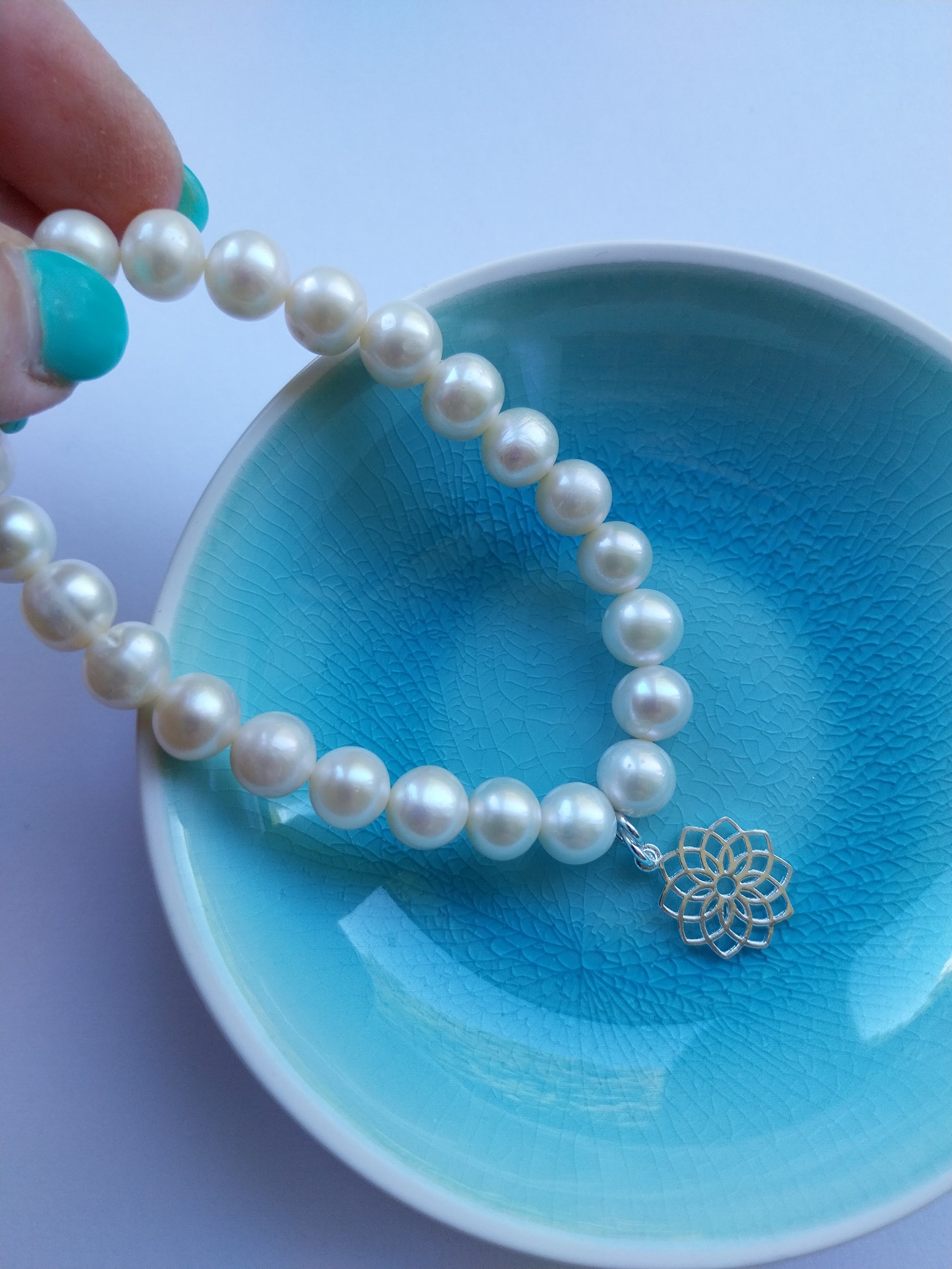 Pearl bracelet featuring a crown chakra silver charm