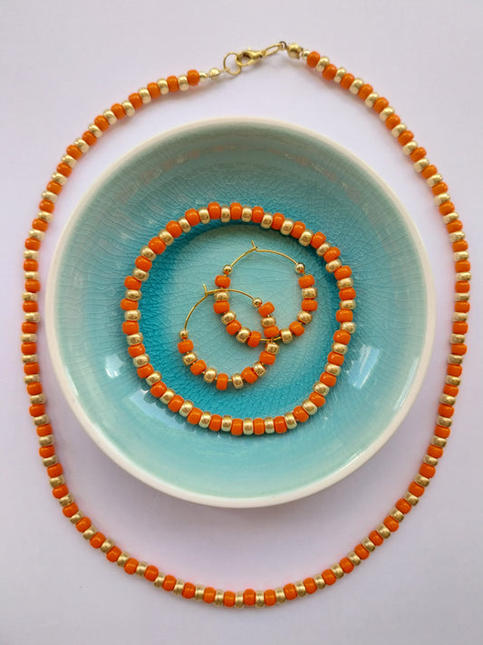 orange and gold glass bead necklace with matching stretchy bracelet and hoop earrings