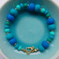 Polymer clay bead bracelet in shades of blue and green with a gold plated heart clasp