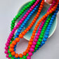 Vibrant clay bead necklaces in blue, orange, magenta and green