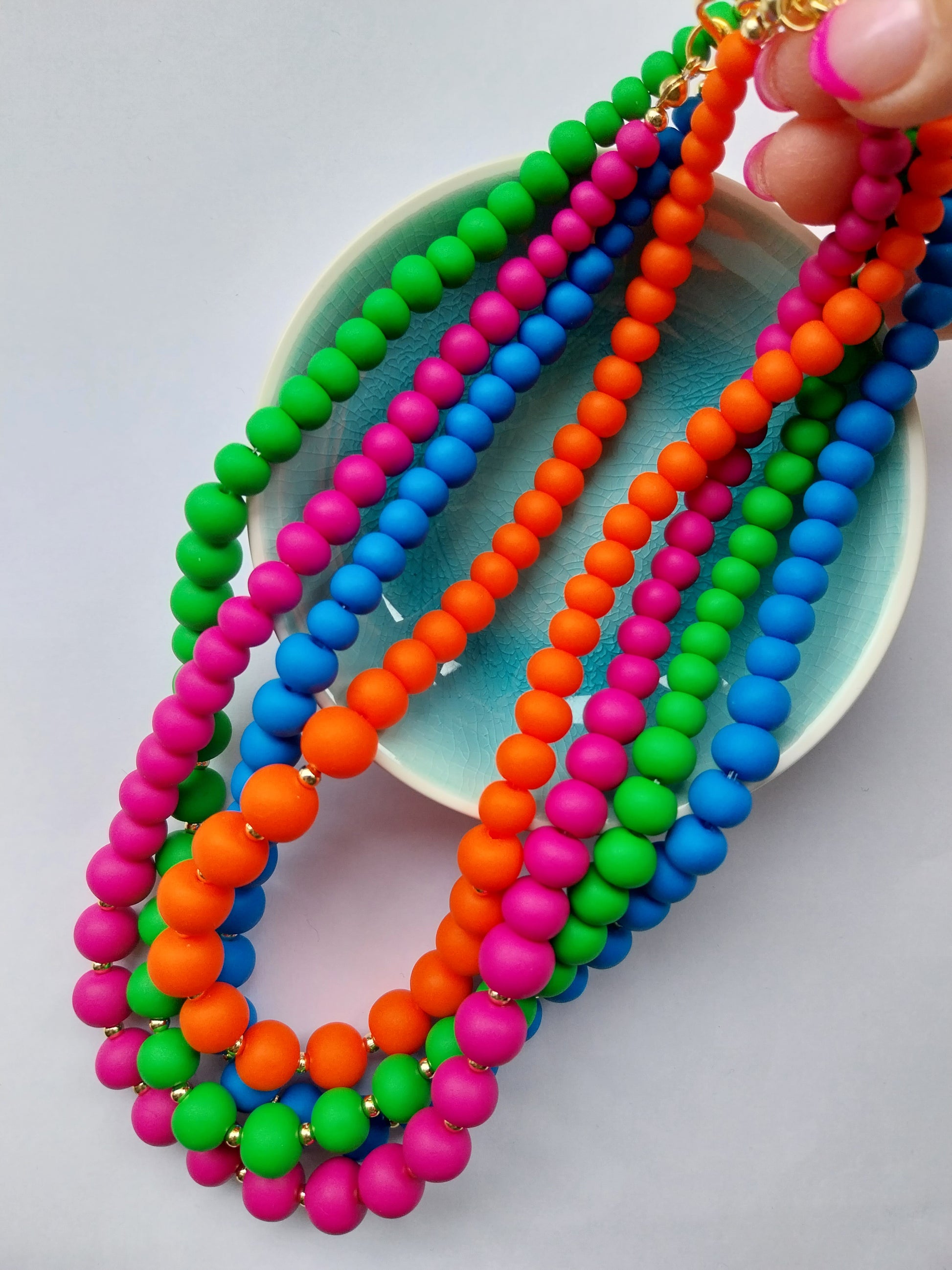 Vibrant clay bead necklaces in blue, orange, magenta and green