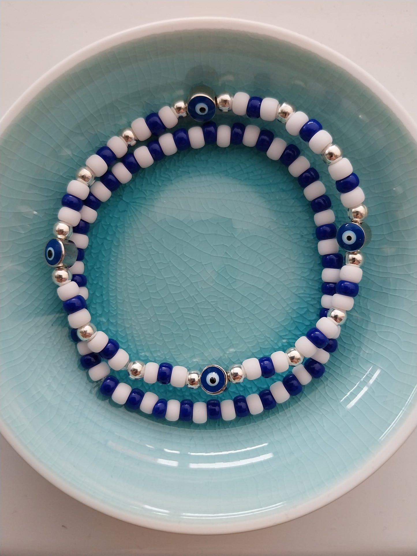 A pair of blue and white bead bracelets one of them features evil eye charm beads