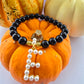 Black agate beaded bracelet with pearl letter E and gold beads on an orange pumpkin