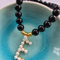 Black beaded agate bracelet with a pearl dangly letter E and gold patterned beads
