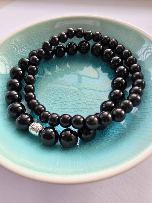 Black agate beaded bracelets with silver bead on a turquoise plate
