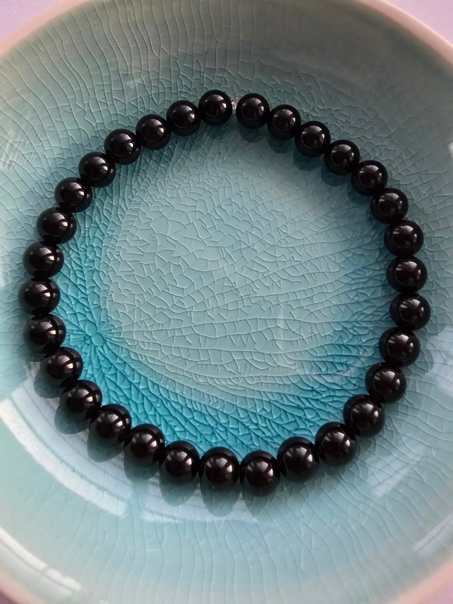 Black beaded agate bracelet on a textured blue plate
