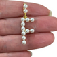Pearl letter 'F' pendant held between fingers on a white background