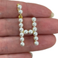 Pearl letter 'H' charm held between fingers against a white background