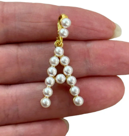 Pearl letter 'A' charm held between fingers on a white background