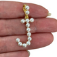 Pearl capital letter J held between fingers on a white background