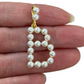 Pearl letter 'B' charm held between fingers on a white background