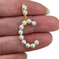 Pearl letter C held between fingers on a white background