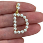 Pearl Letter capital D held between fingers against a white background