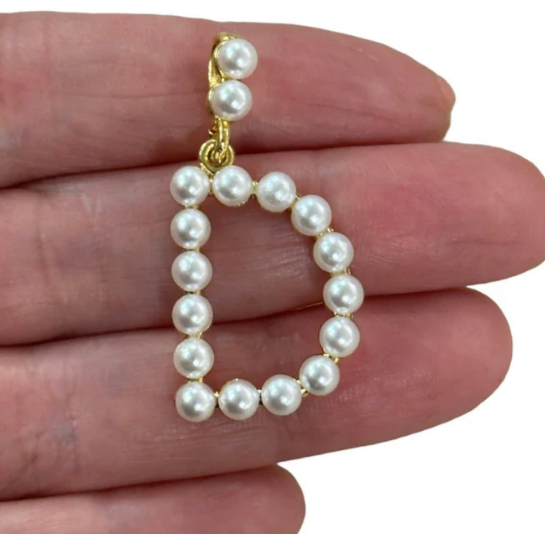 Pearl Letter capital D held between fingers against a white background
