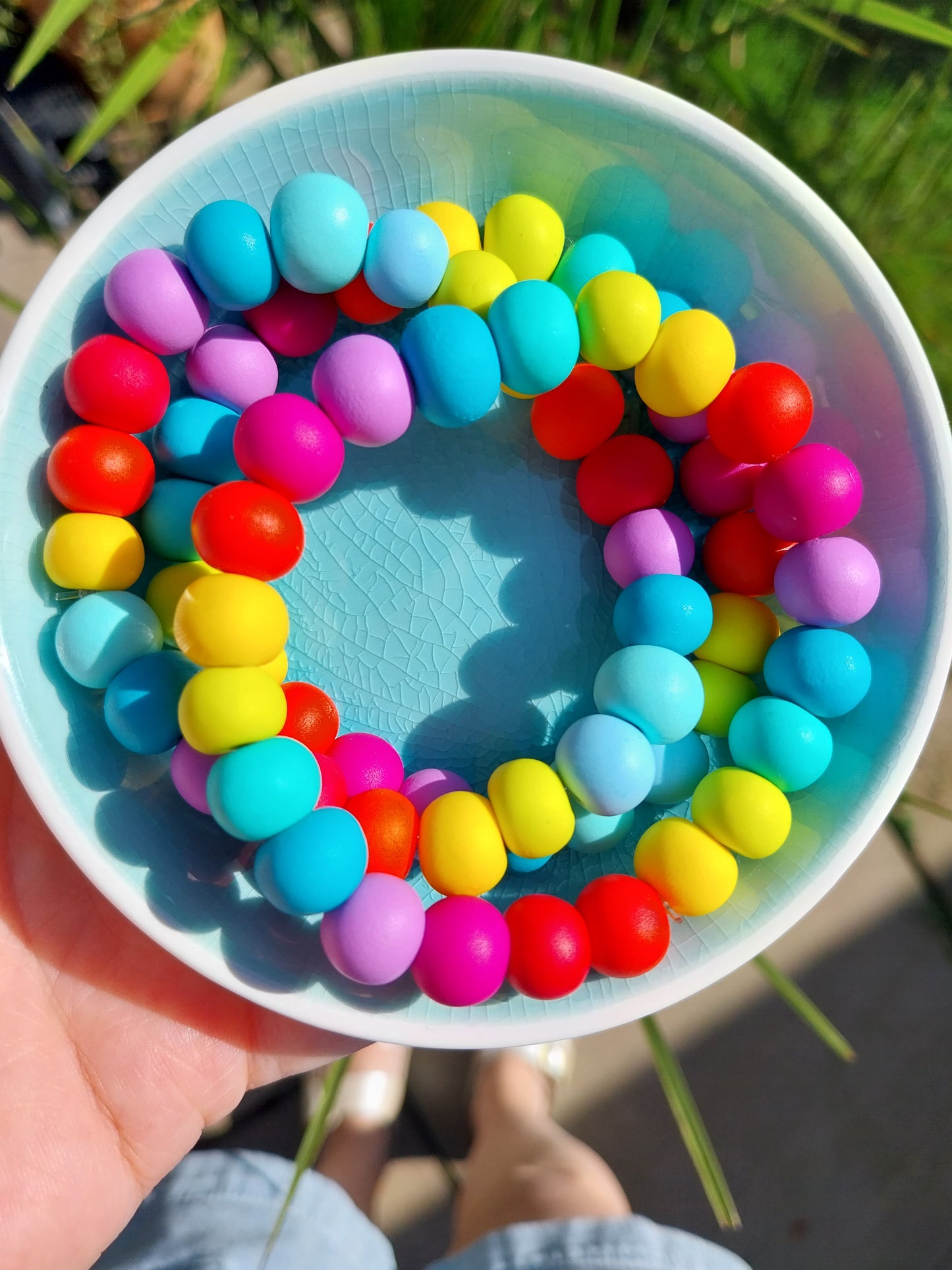 Rainbow coloured clay bead bracelets stacked together